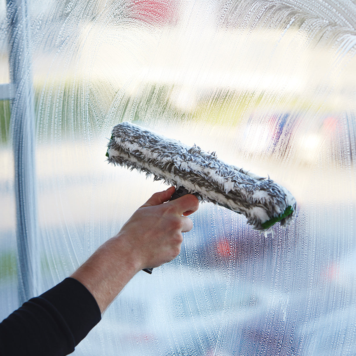 Hand hält ErgoTec NinJa Einwascher bei professioneller Fensterreinigung im Einsatz.