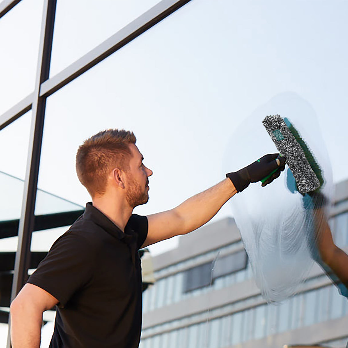 Mann reinigt Fenster mit UNGER ErgoTec 2in1 Starterset; hochwertige Glasreinigungswerkzeuge in Aktion.