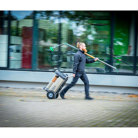 Person zieht UNGER HydroPower RO S Reinwasseranlage auf einem Wagen vor einem Gebäude.